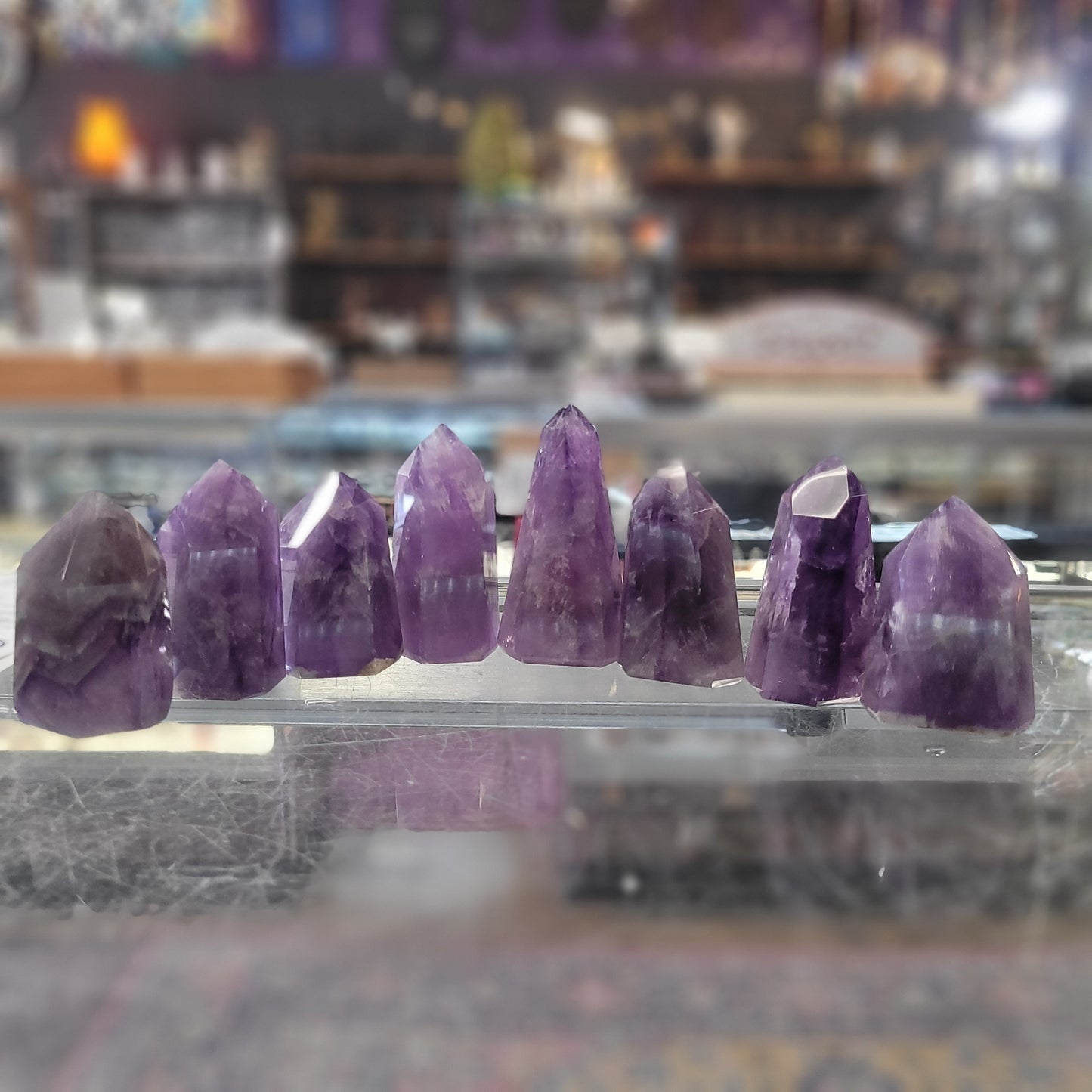 Purple crystal points on a reflective surface with a blurred store interior in the background
