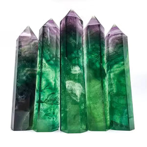 Five tall, faceted crystal towers with a gradient from deep green to purple, standing against a plain white background.