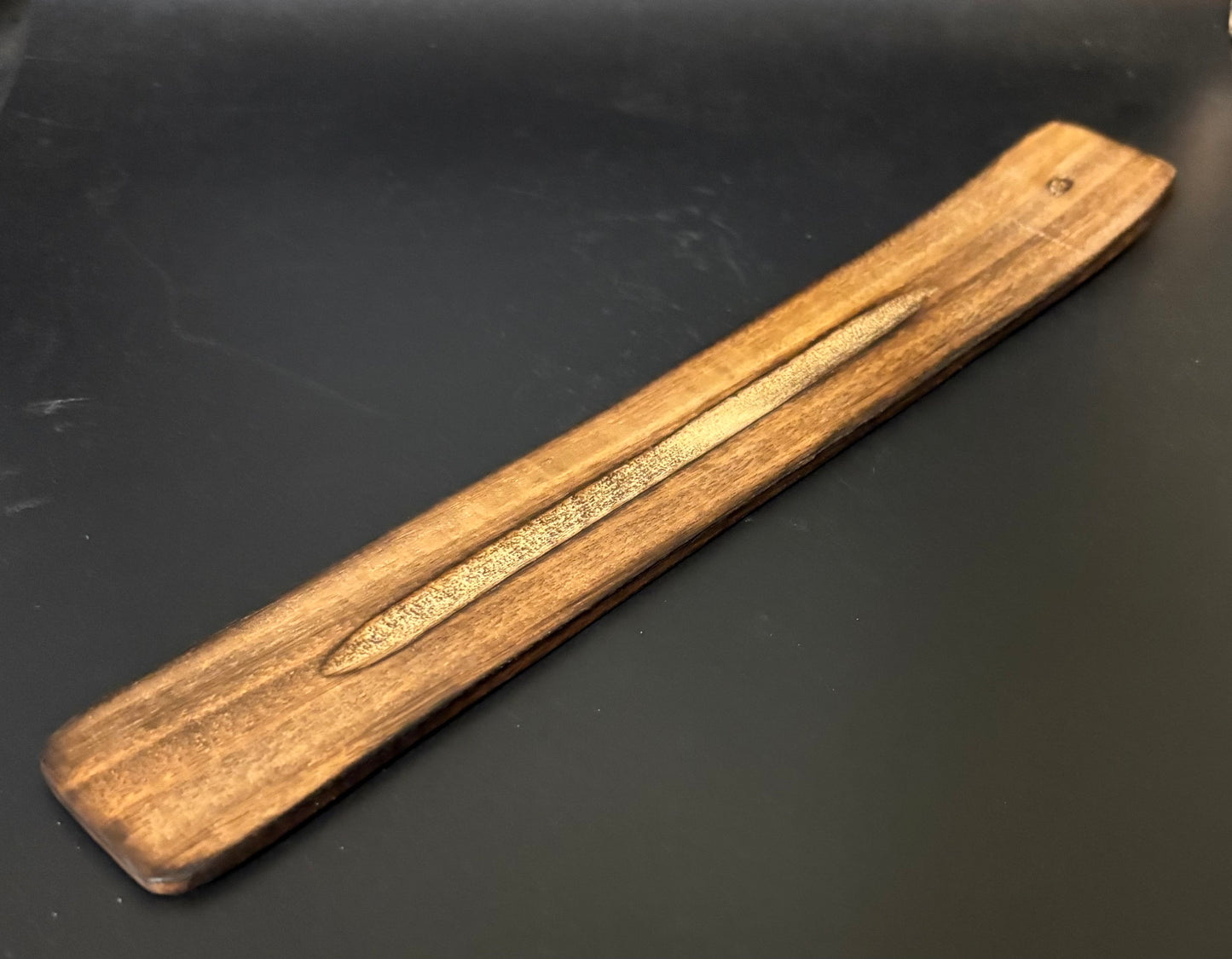 Wooden incense holder on a dark surface