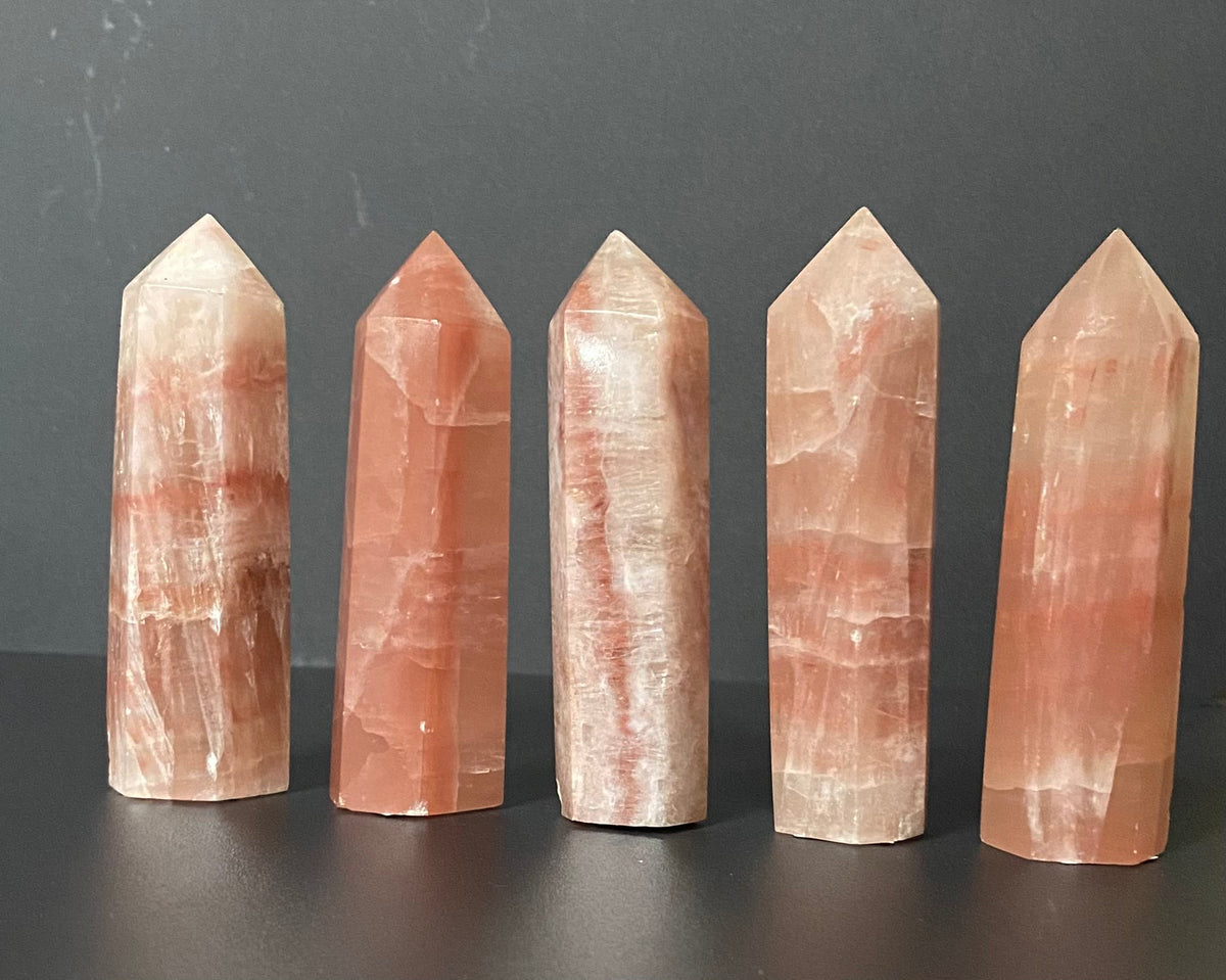 Five pointed crystal tower pendants made of lepidocrocite, arranged in a row against a dark gray background.