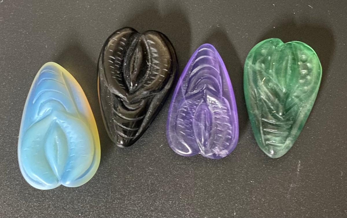 Vulva carved stone amulets on a black background