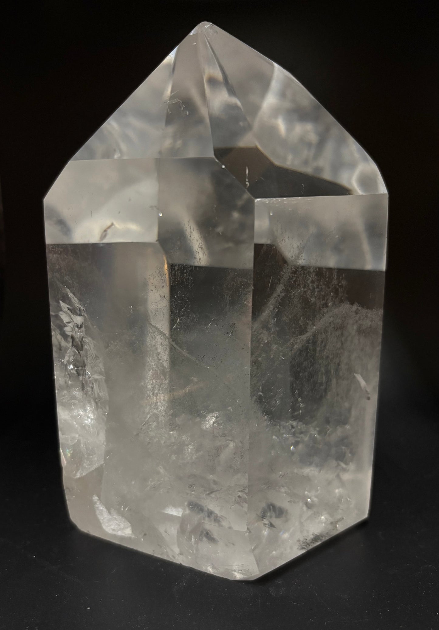 A clear quartz crystal point tower with natural inclusions, photographed against a solid black background.