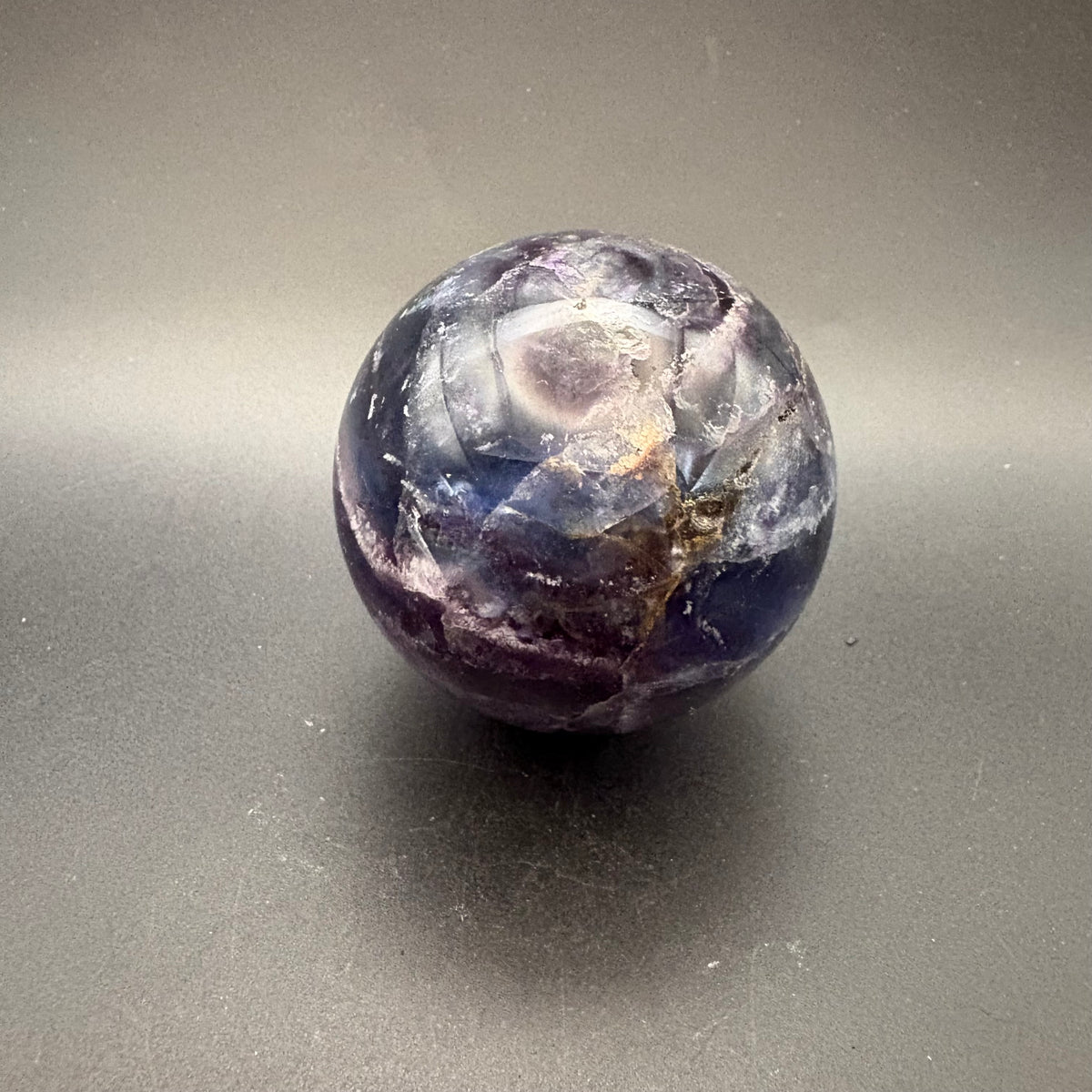 Blue and purple polished fluorite sphere on black background