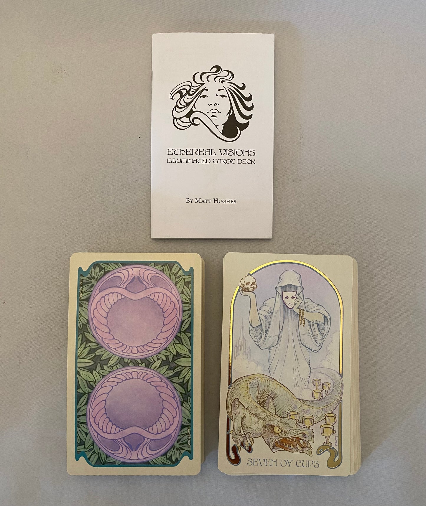 Two tarot cards and a book titled 'Eccentric Visions' on a gray background