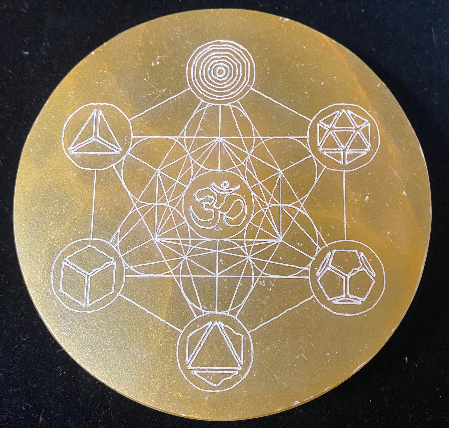 Circular object with white geometric line art on a dark background