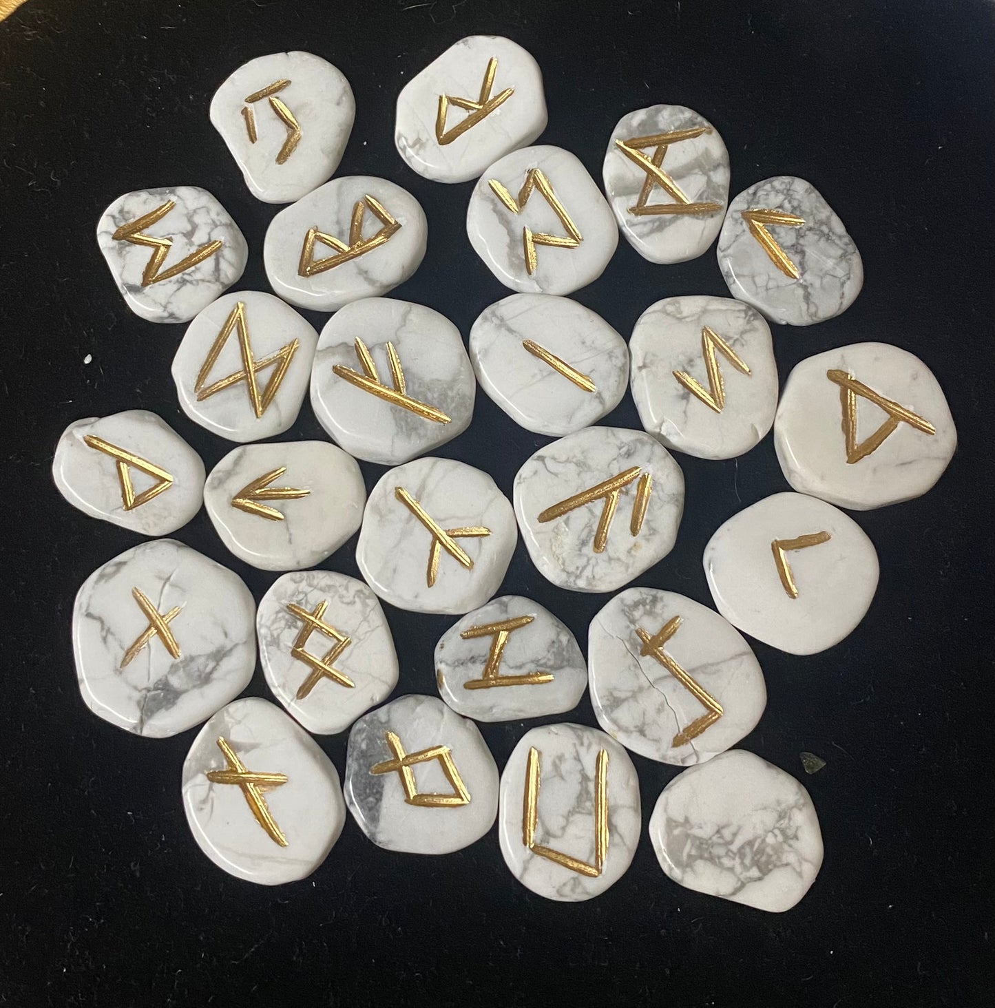 Rune Set Howlite stones with gold runes on a black background