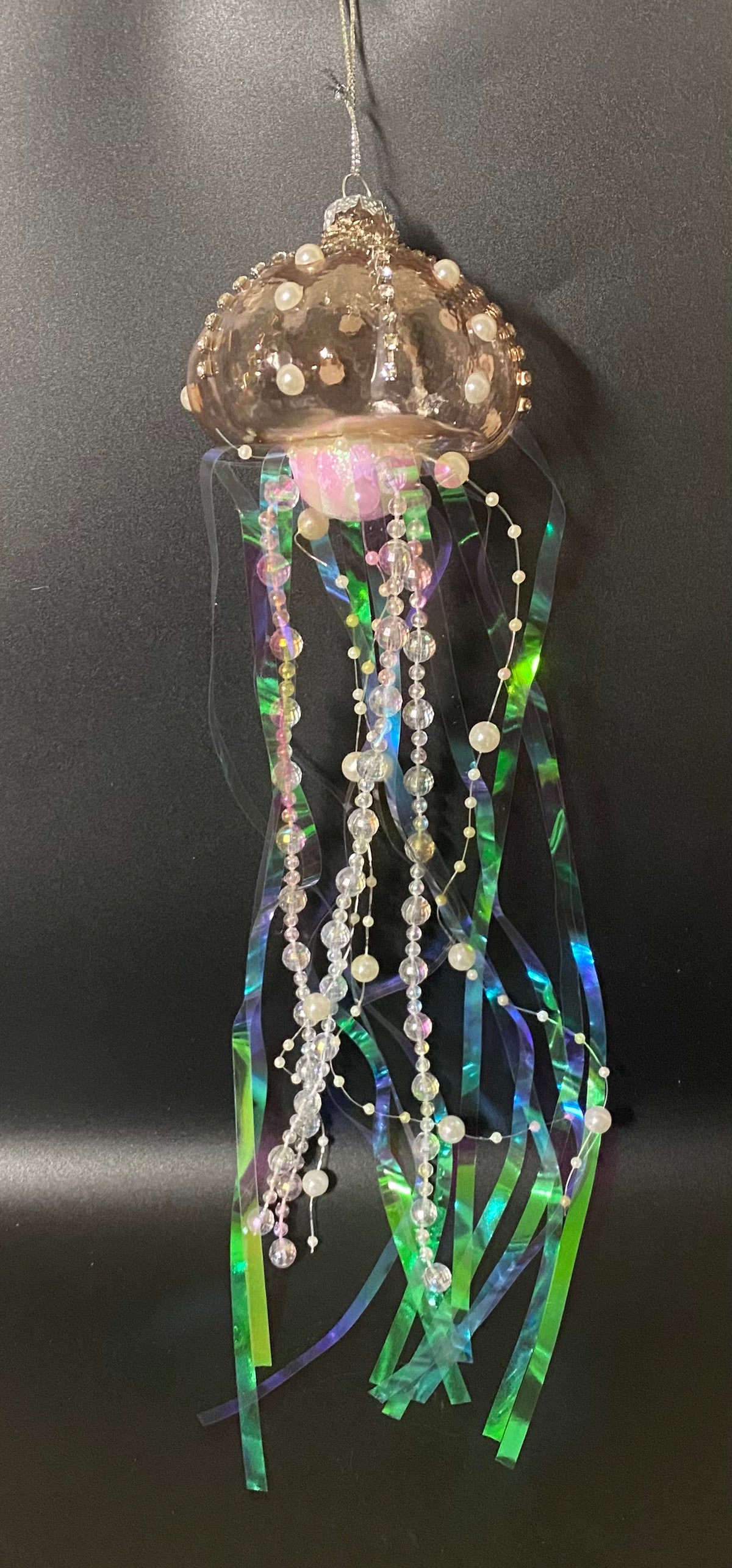 Decorative jellyfish ornament with ribbons and beads on a black background