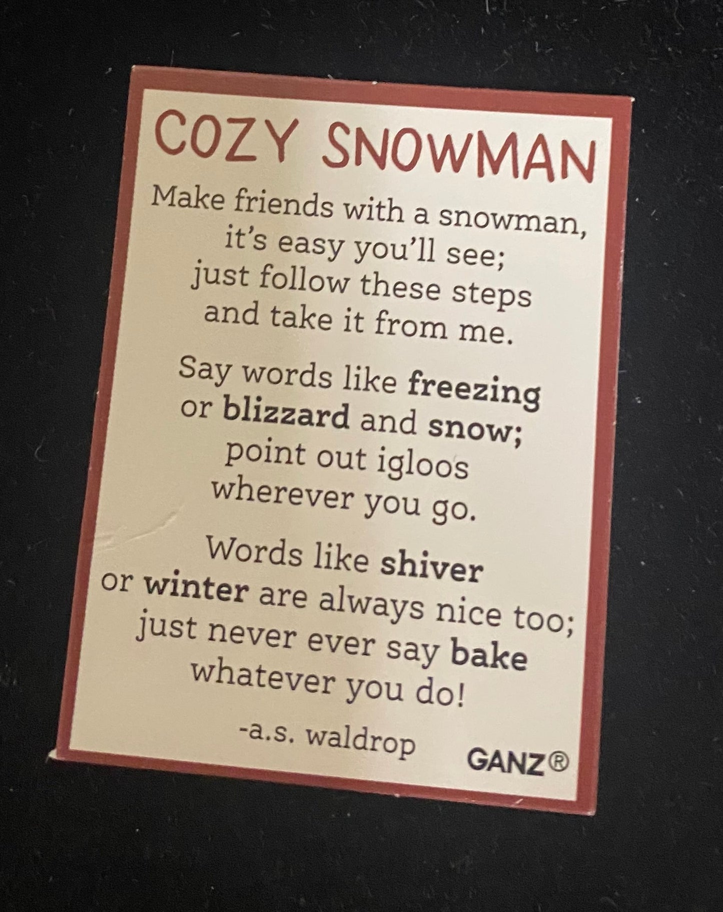 Charm Card for a 'Cozy Snowman' with text on a black background