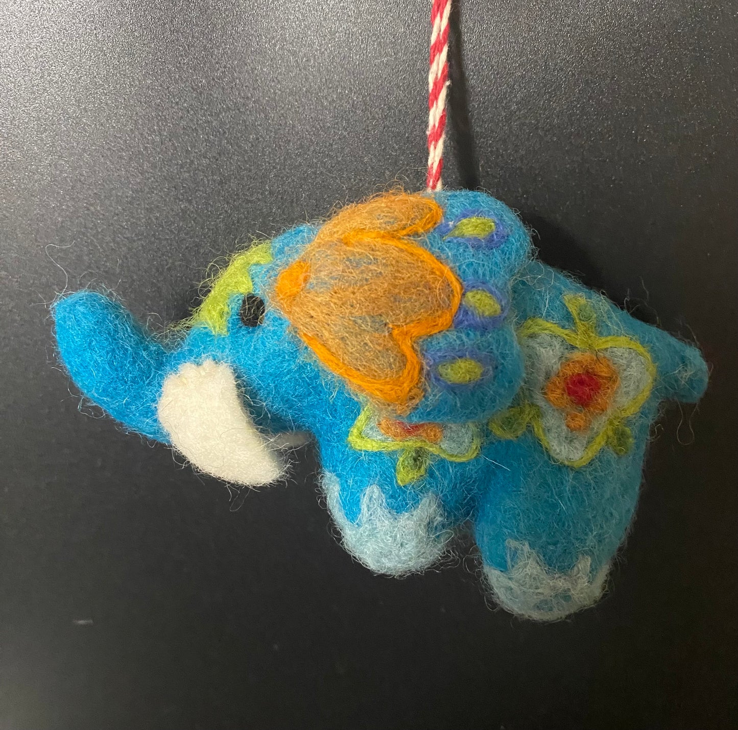 Colorful felted elephant ornament on a black background