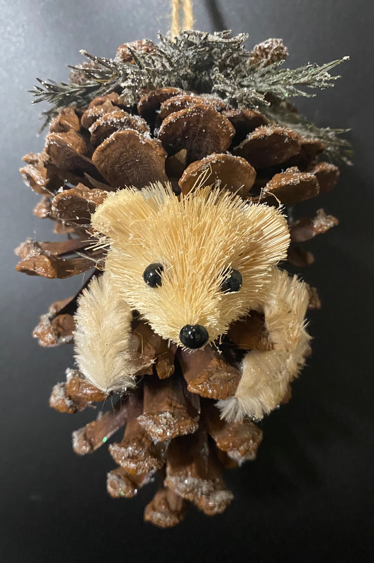 Hedgehog ornament made from pine cones and faux fur on a dark background