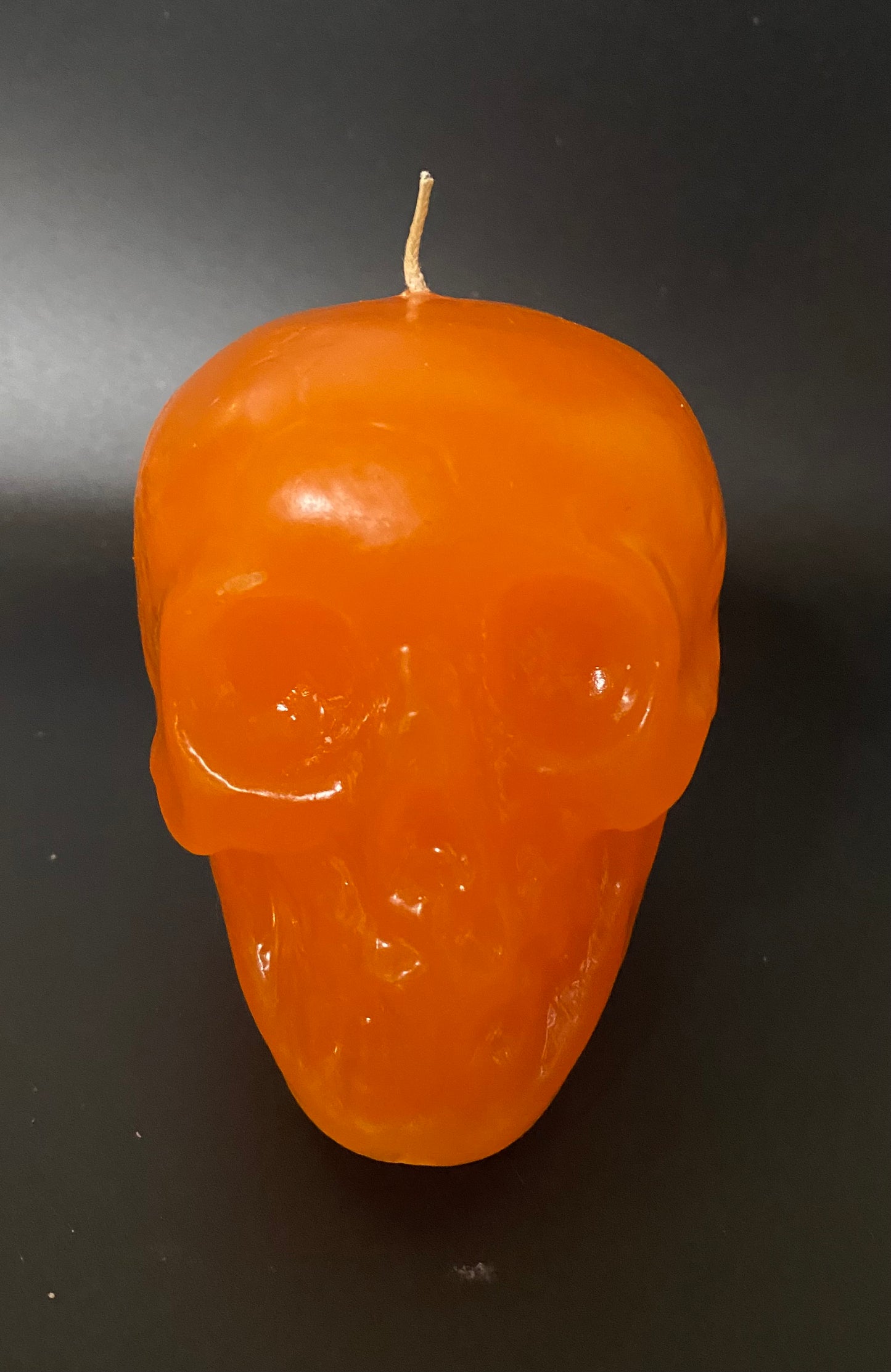 Orange skull-shaped candle on a black background