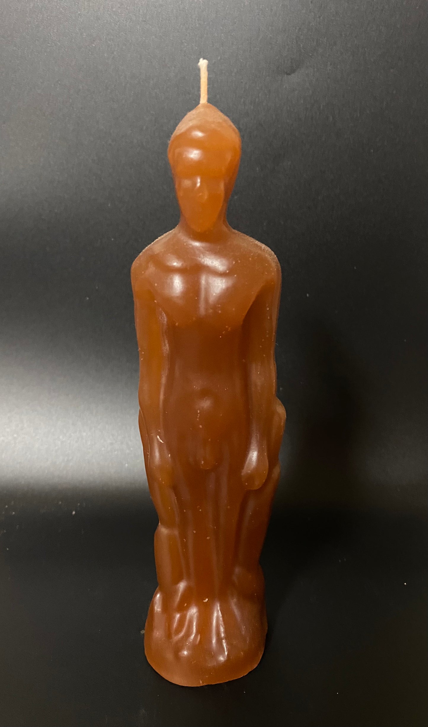 Candle shaped like a standing figure on a black background