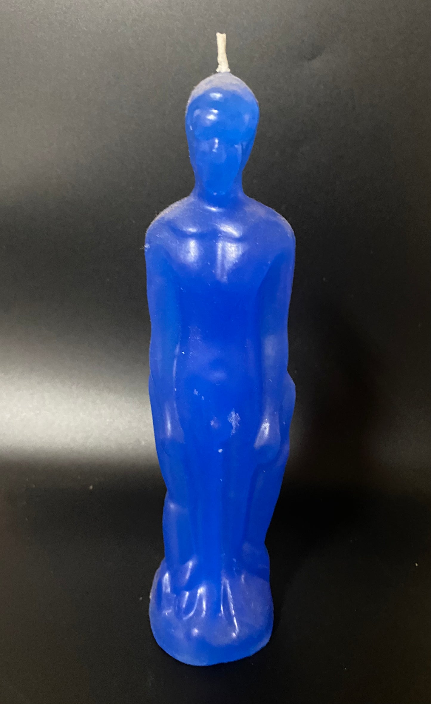 Blue candle shaped like an Oscar statue on a black background