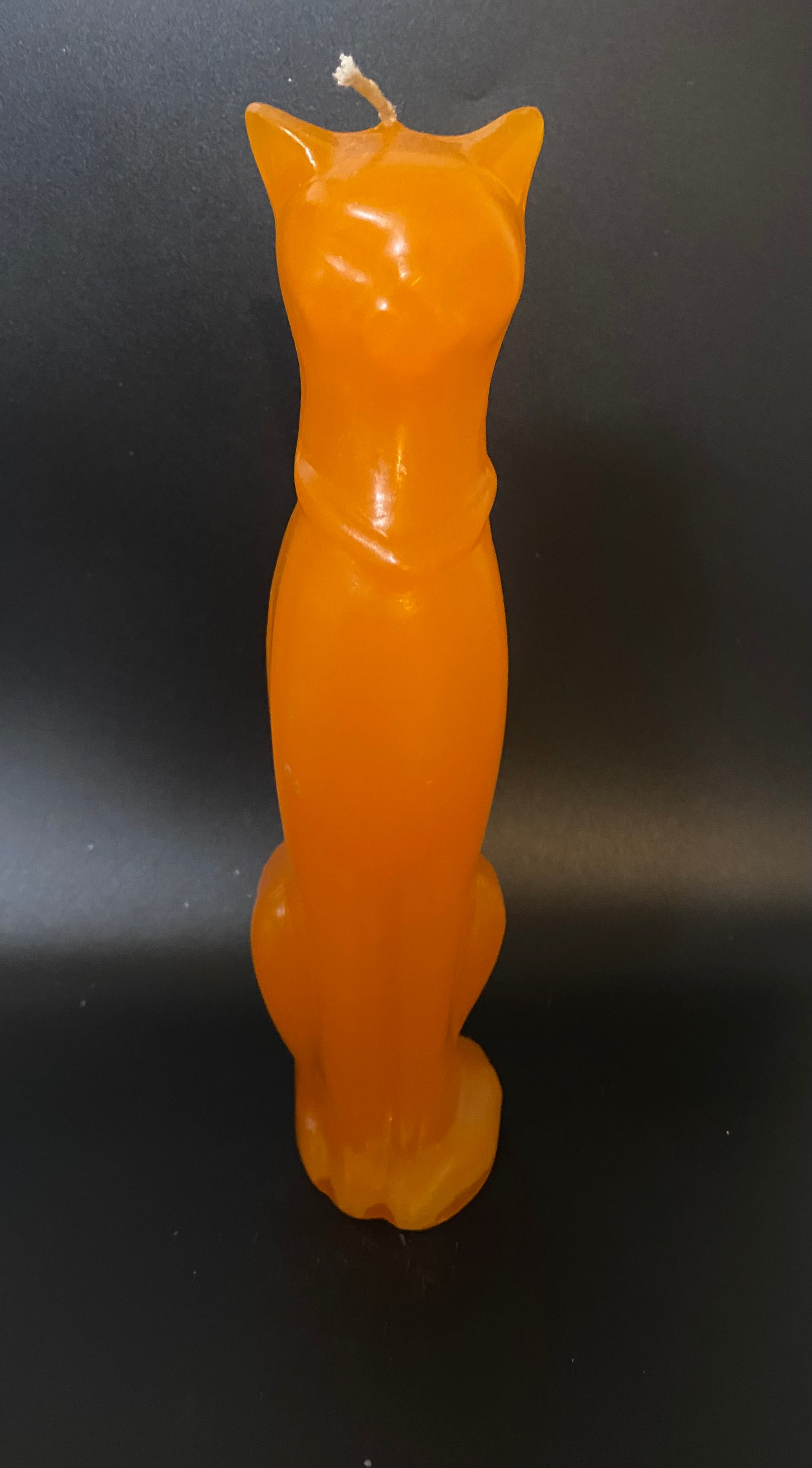 Orange cat-shaped candle on a black background