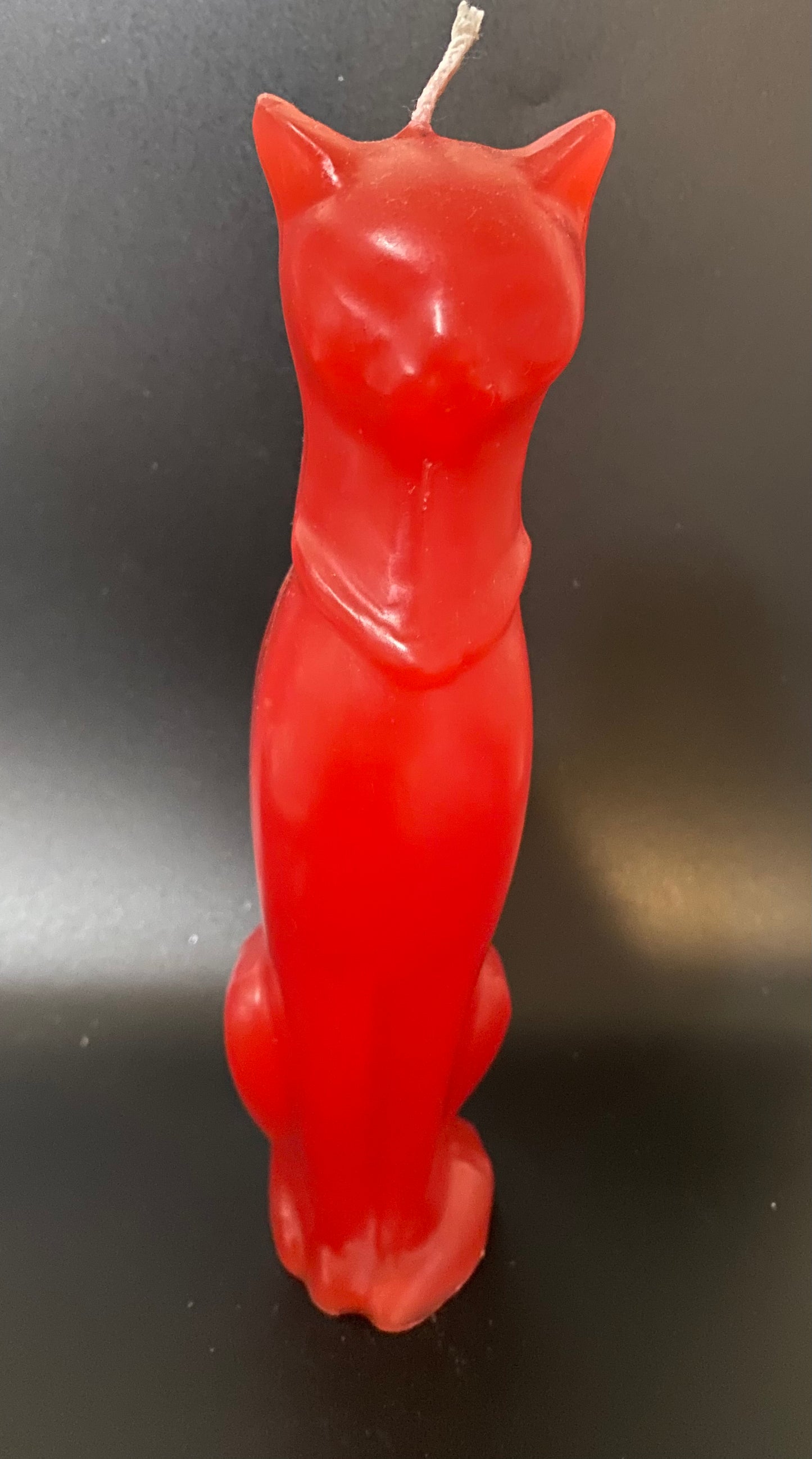 Red cat-shaped candle on a black background