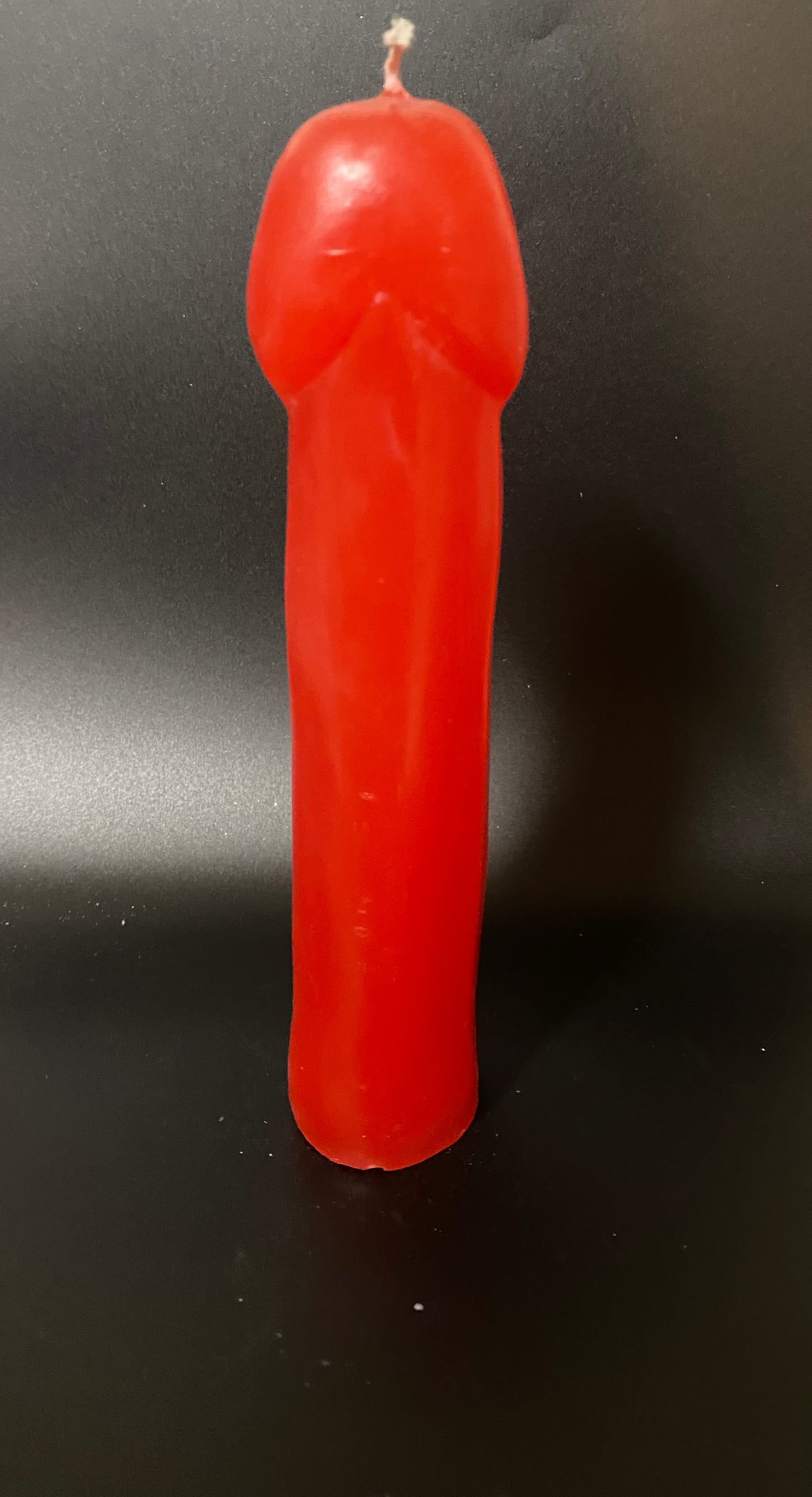 Red candle shaped like a gun on a black background