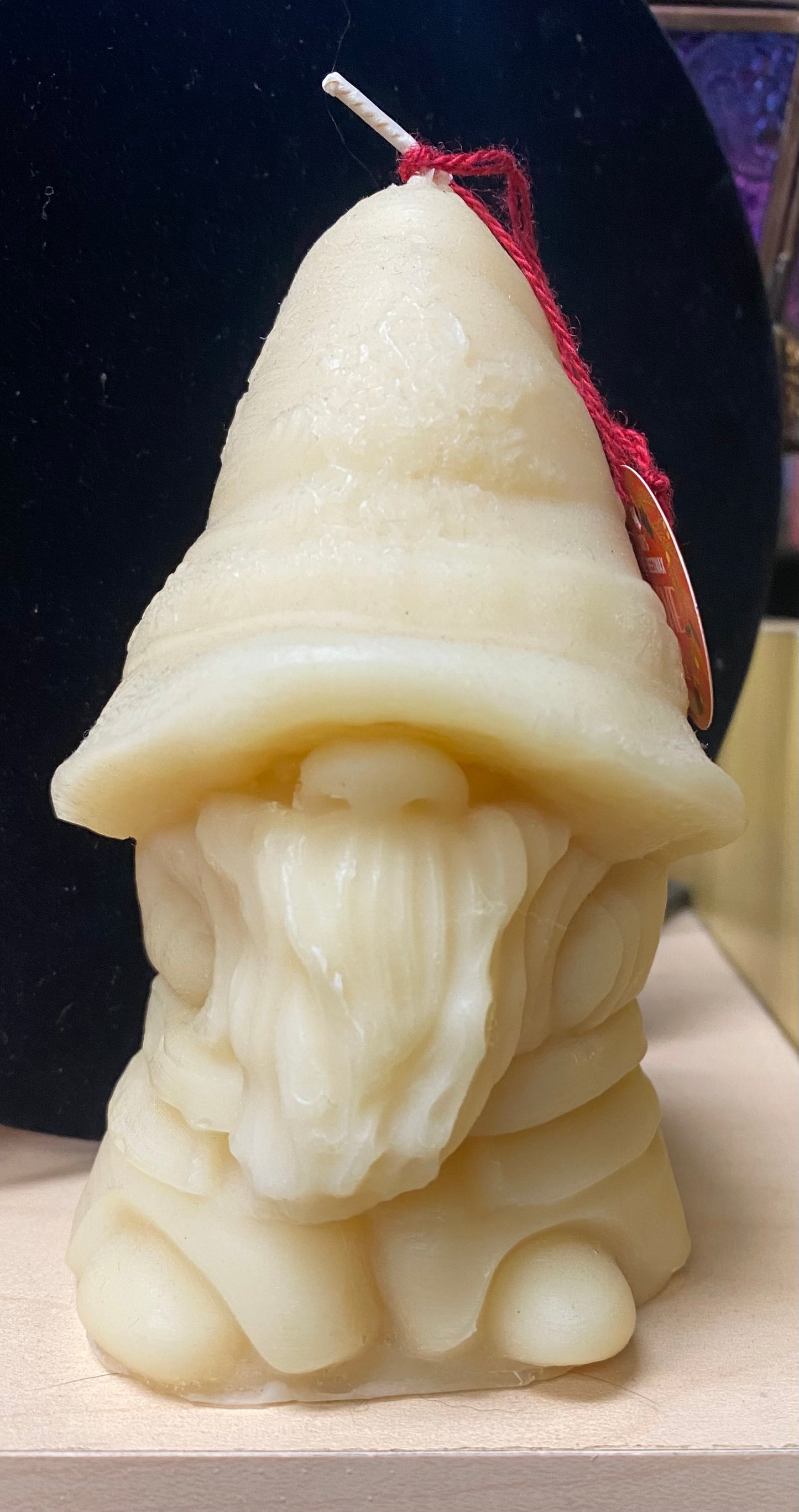 Candle shaped like a gnome with a pointed hat on a dark background