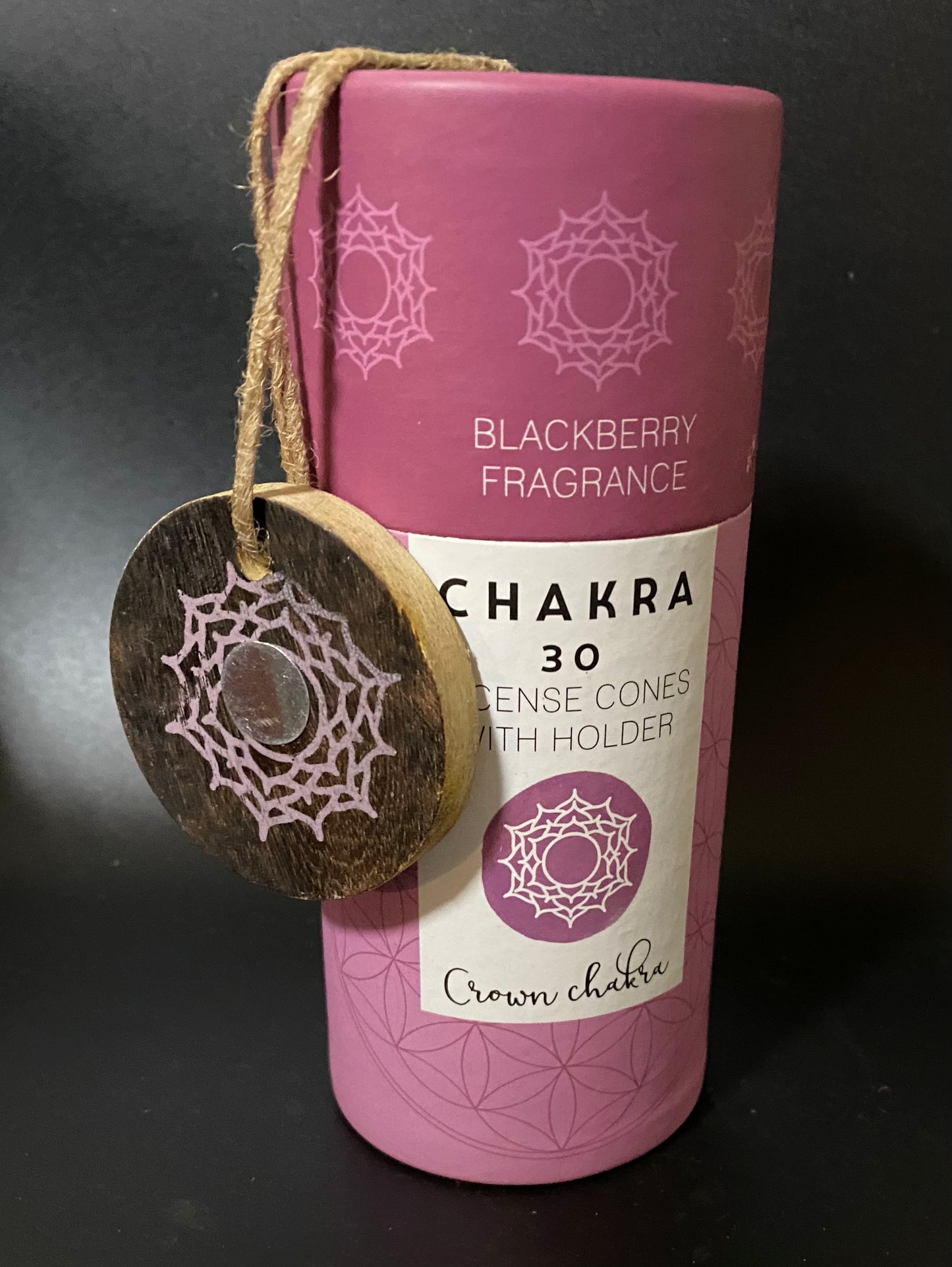 Pink container of Chakra incense cones with a wooden tag on a dark background