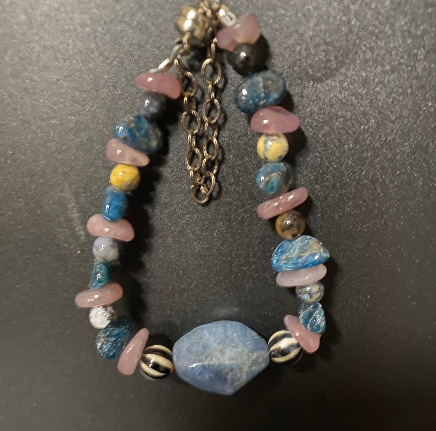 Multicolored beaded bracelet with a chain on a dark background