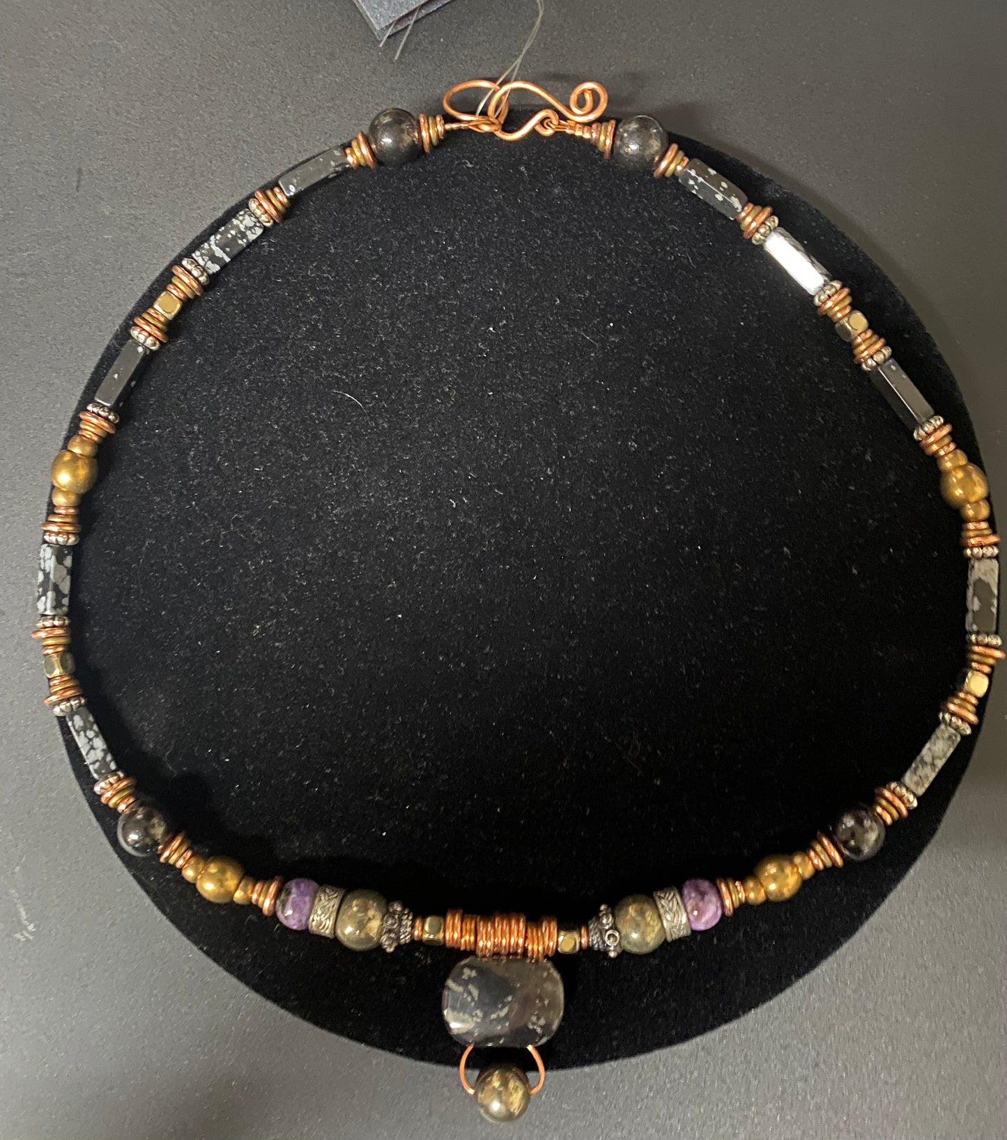 Beaded necklace with a pendant on a black stand