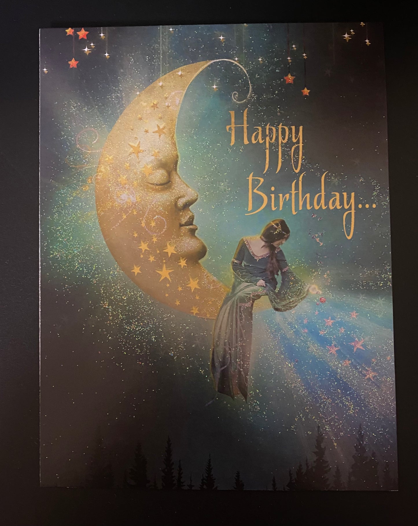 Greeting card with a celestial design featuring a face on a moon and a person, with 'Happy Birthday' text.