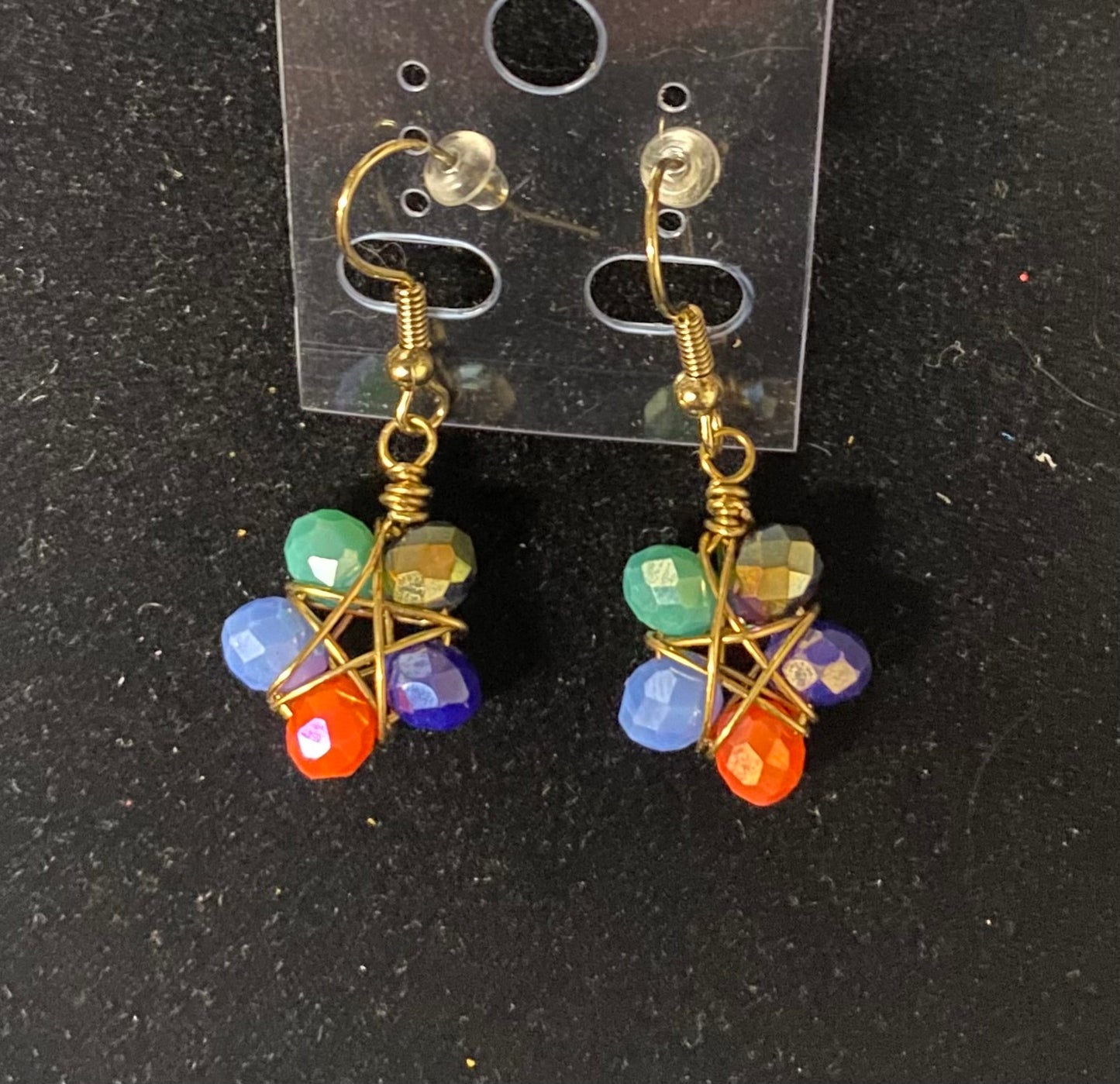 Colorful beaded earrings on a clear card against a black background