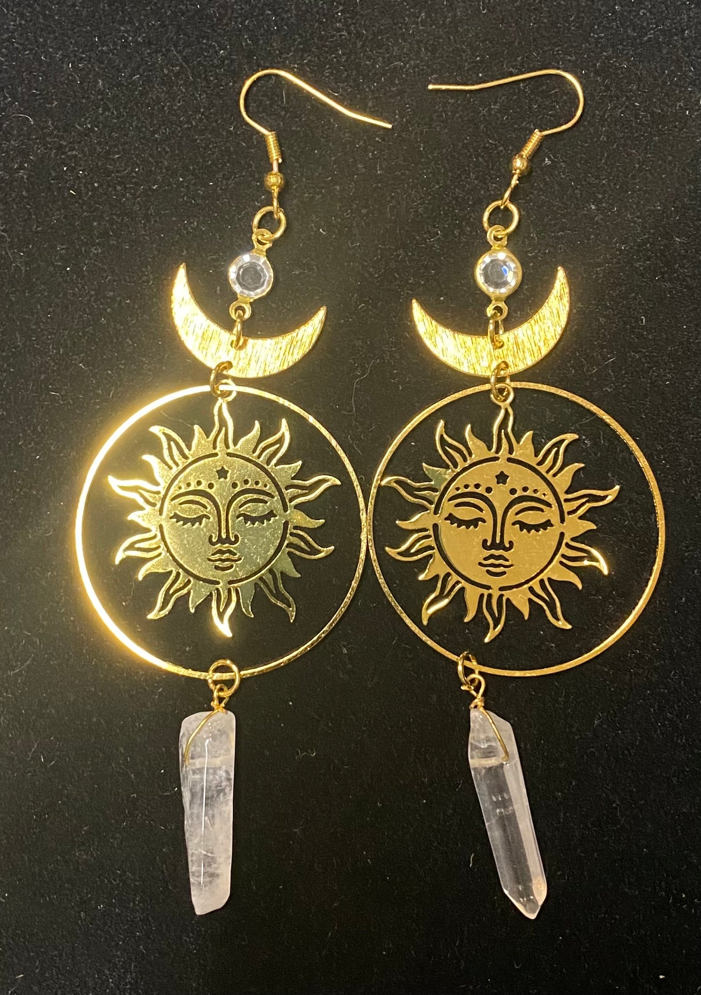 Gold sun and moon earrings with crystal pendants on a black background