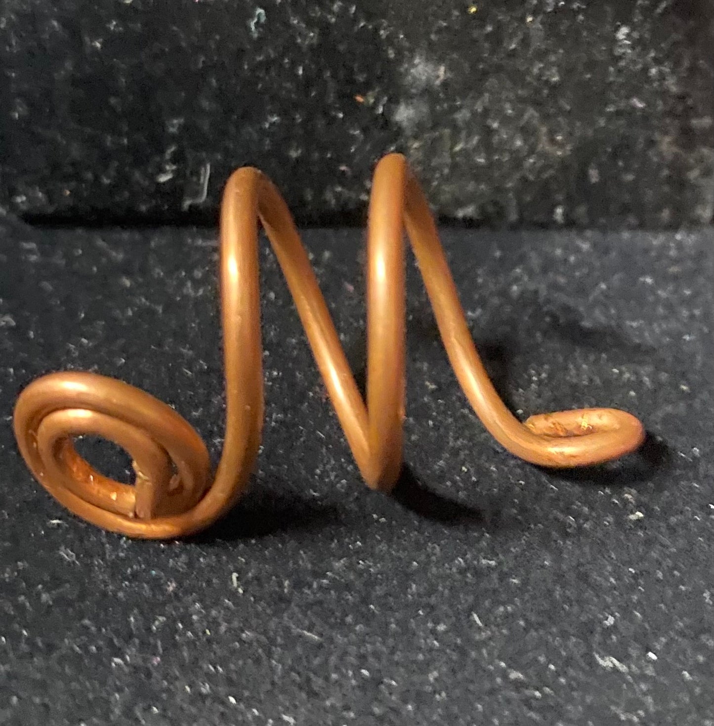 Copper spiral ring on a black textured background