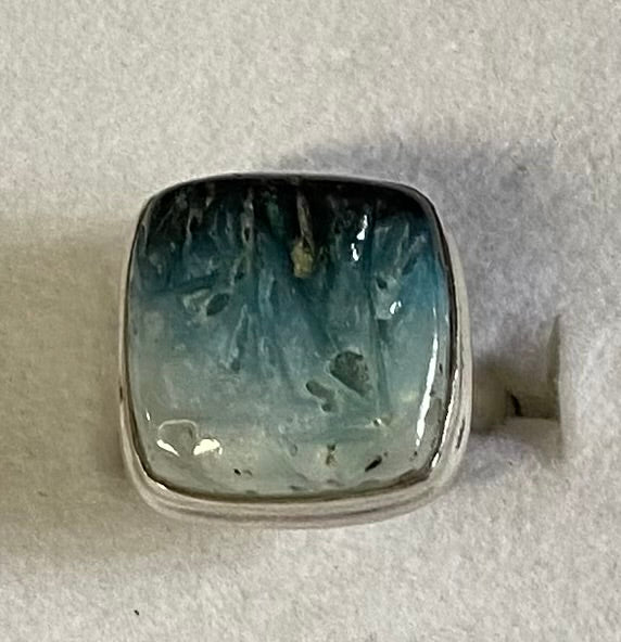 Silver ring with a large blue stone on a gray background