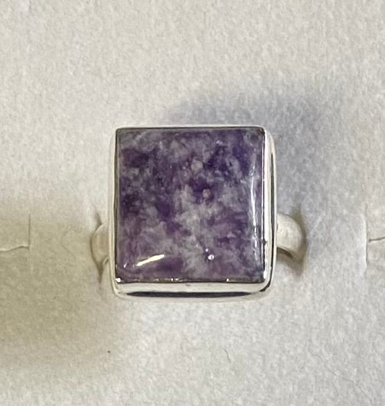 Silver ring with a square purple stone on a light gray background