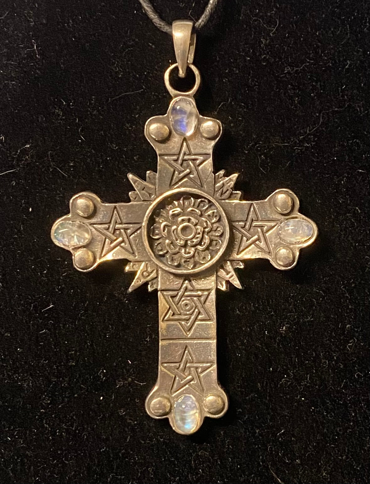 Silver cross pendant with star designs on a black background