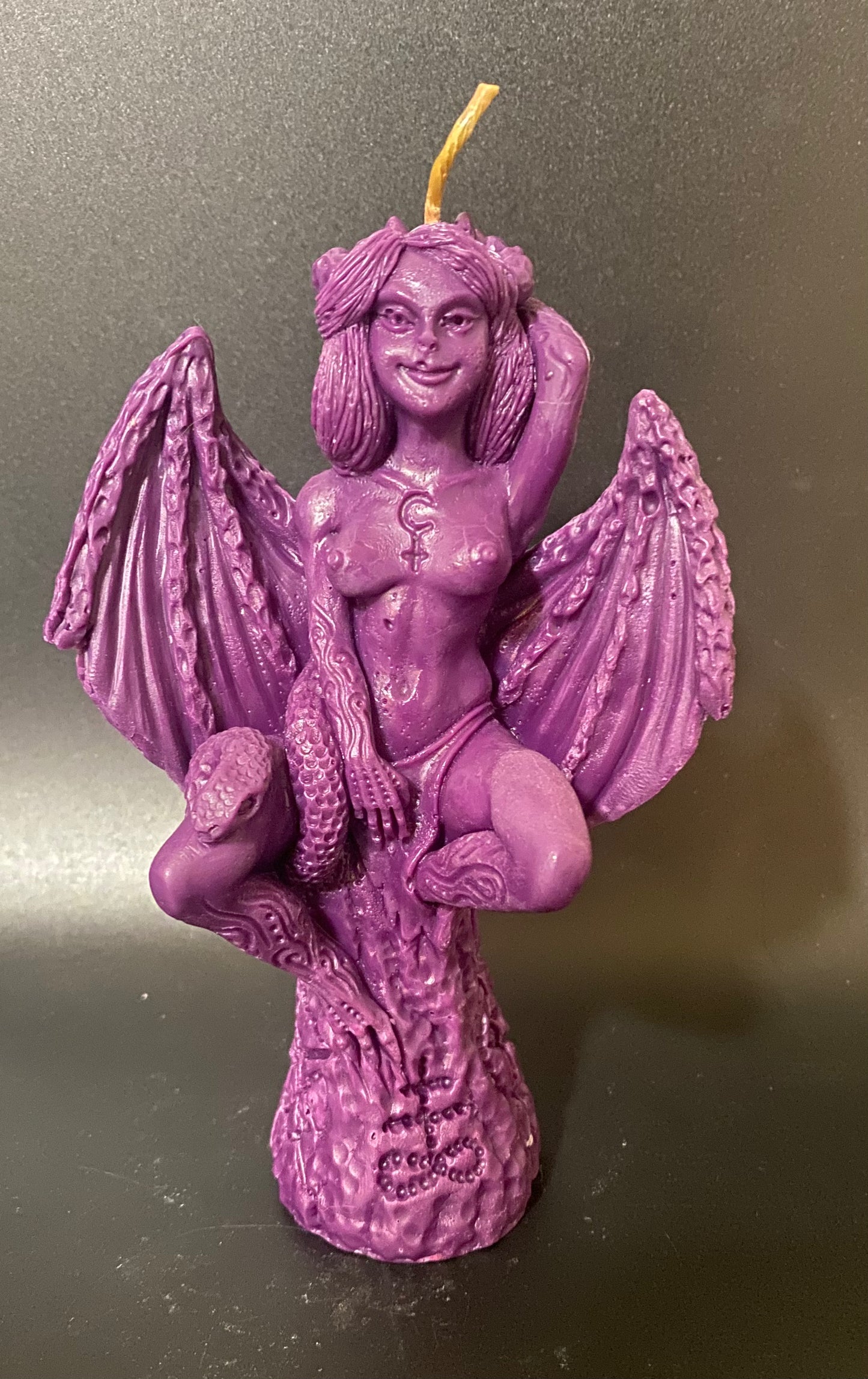 Purple candle with angelic figure on a dark background