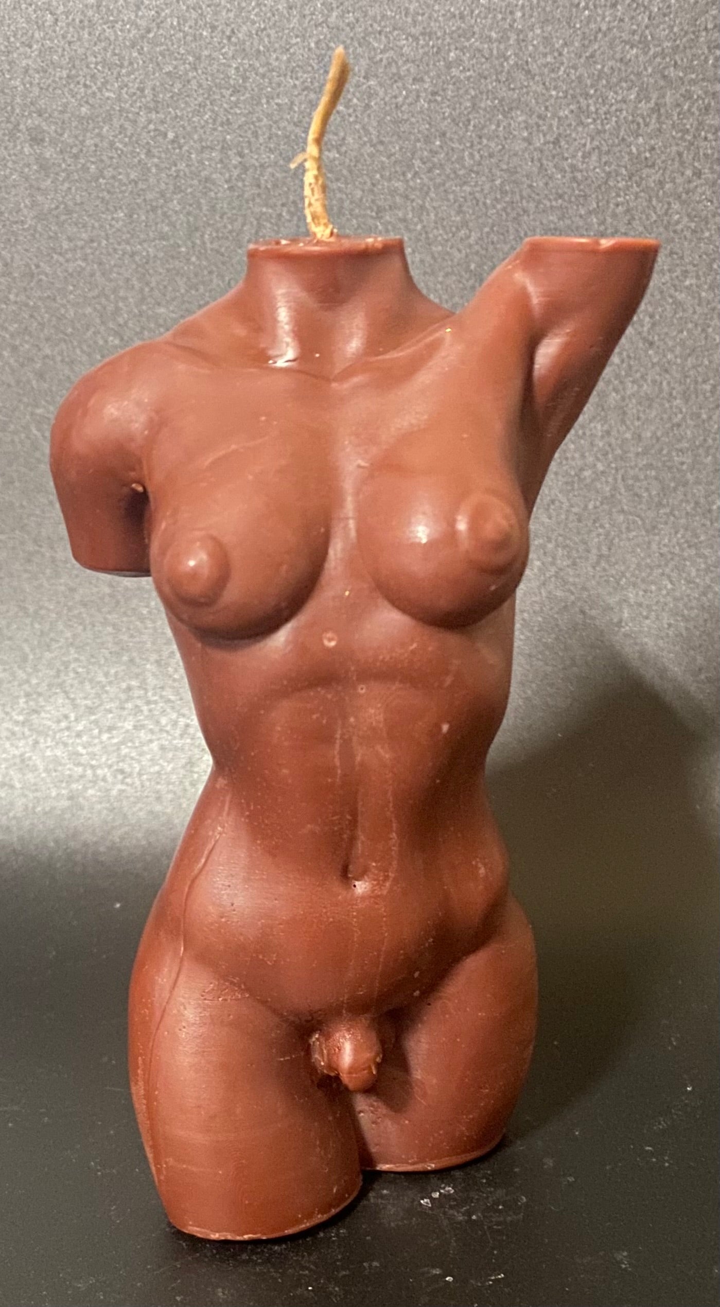 Candle shaped like a human torso on a gray background