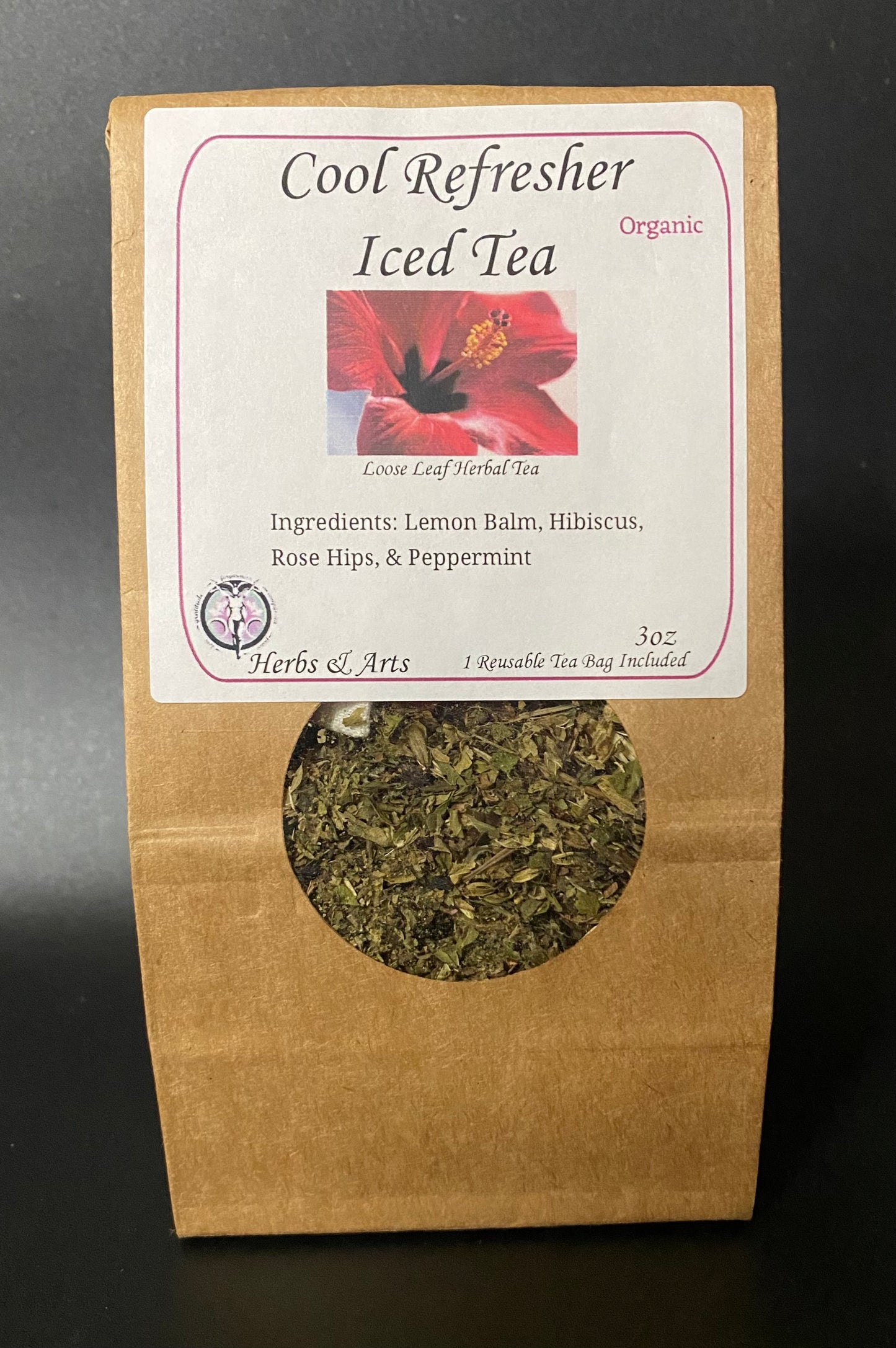 A kraft paper stand-up pouch of Coole Leaf Herbal Tea, labeled 'Cool Refresher Iced Tea Organic,' with a circular cutout showing dried green tea leaves inside. The front label includes a red hibiscus flower photo and the brand name Herbs & Arts on a dark background.