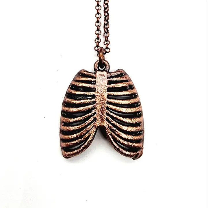 Bronze ribcage pendant on a chain against a white background