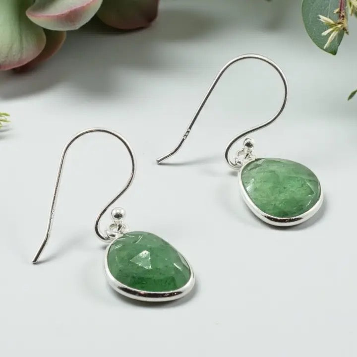 Green stone earrings with silver hooks on a light background