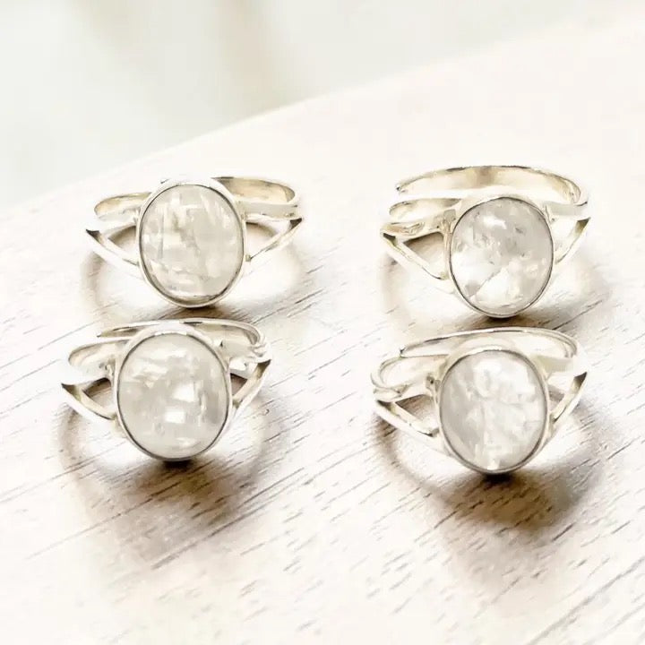 Set of silver rings with moonstone stones on a light wooden surface