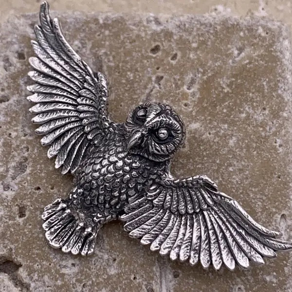Silver owl figurine on a textured stone surface