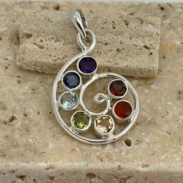 Silver pendant with colorful gemstones on a stone surface