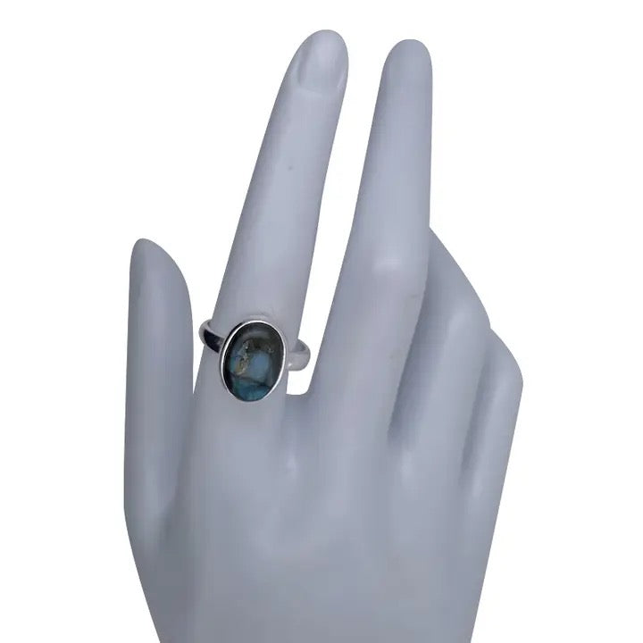 Silver ring with a blue gemstone on a gray mannequin hand