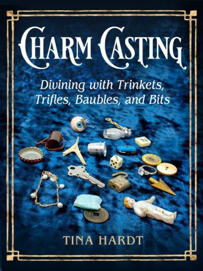 Book cover of 'Charm Casting' with various trinkets on a blue background