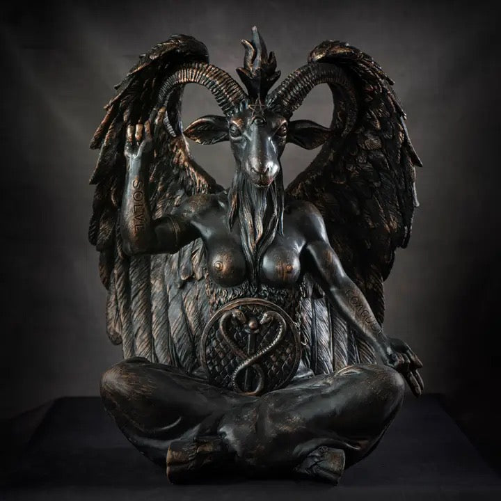 A dark bronze-finished statue of a winged goat-like female figure seated cross-legged, photographed against a dark studio background.