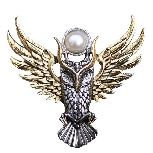 Decorative brooch with owl design, gold wings, and pearl center on a white background