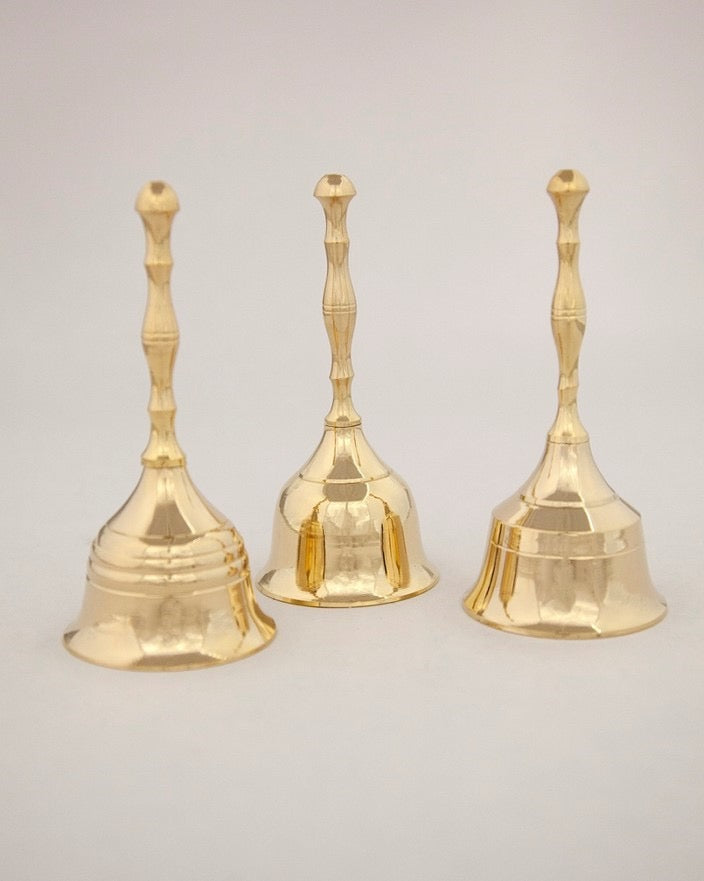 Three gold bells with textured handles on a light gray background