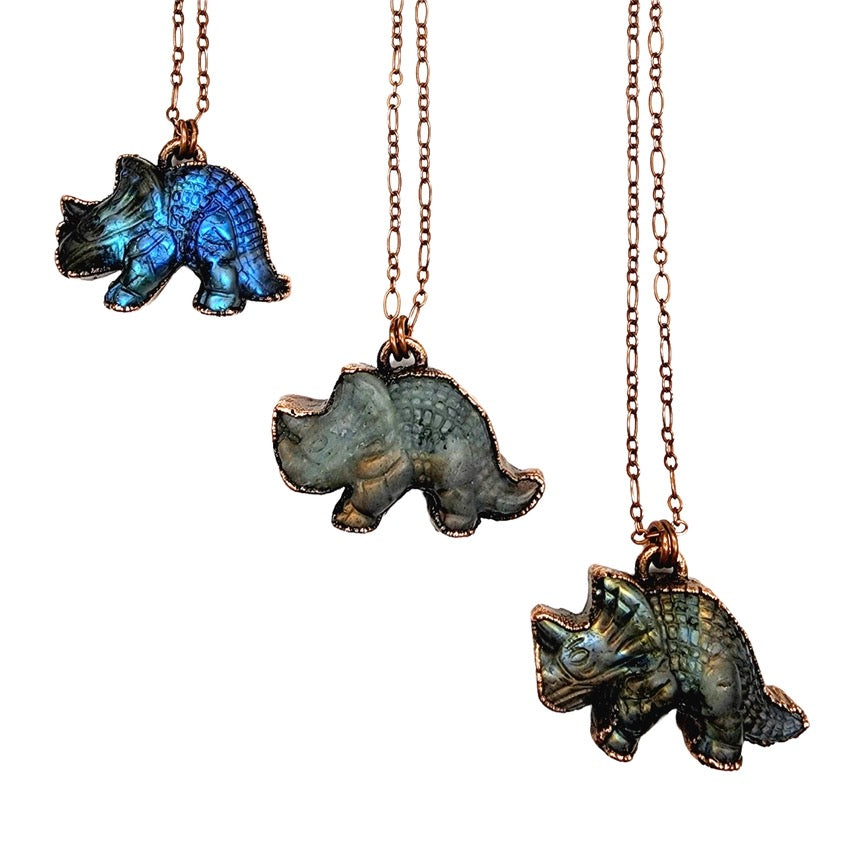Three dinosaur-shaped pendants on chains against a white background