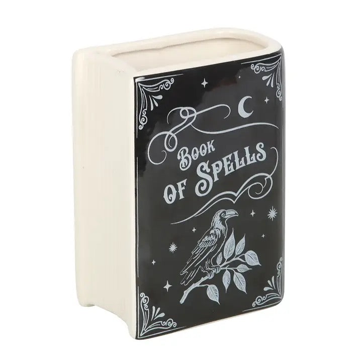 Decorative book-shaped container with 'Book of Spells' text and a raven illustration on a white background.