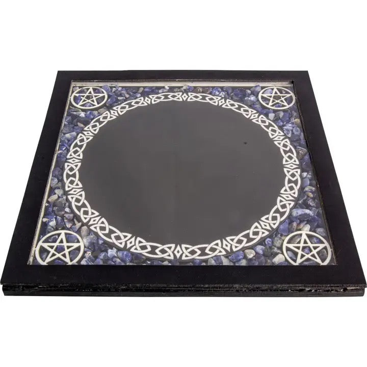 A square black-framed mirror with a mystical design. The inner surface features a large black circular center, surrounded by a white Celtic knot border and four white pentagrams set against a background of blue and purple stones.