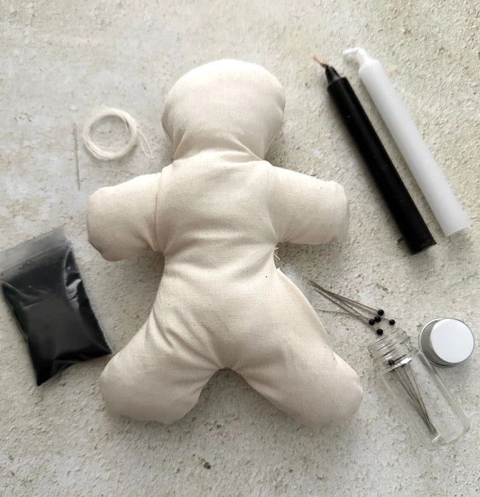 Unfinished plush doll on a concrete surface with tools and materials around