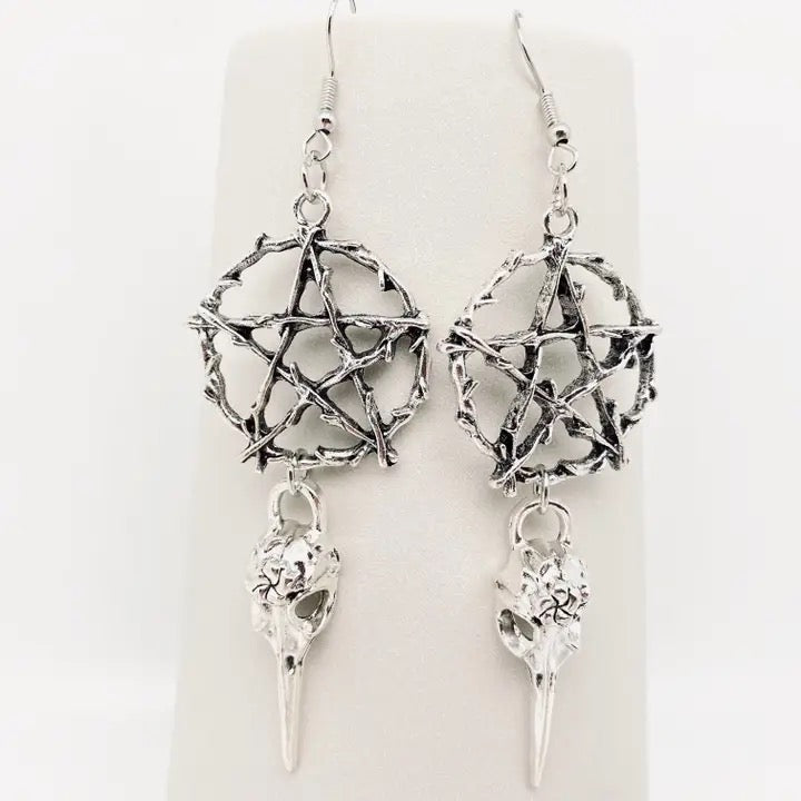 Silver pentagram earrings with bird skull pendants on a white background