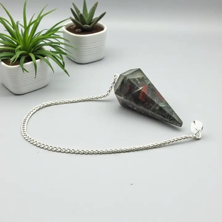 Pendulum Bloodstone with plants and a white table top.